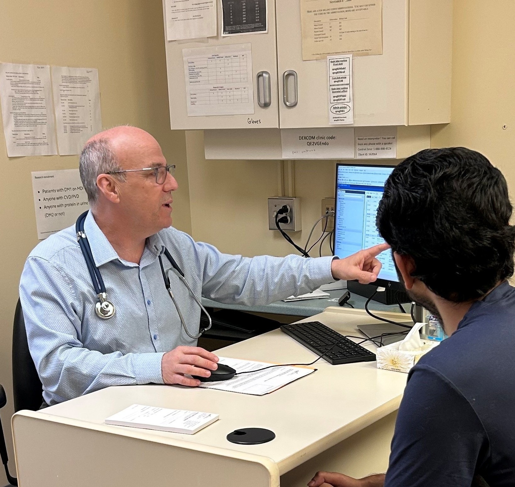 Dr. Ransom in an office showing a screen to a patient. 